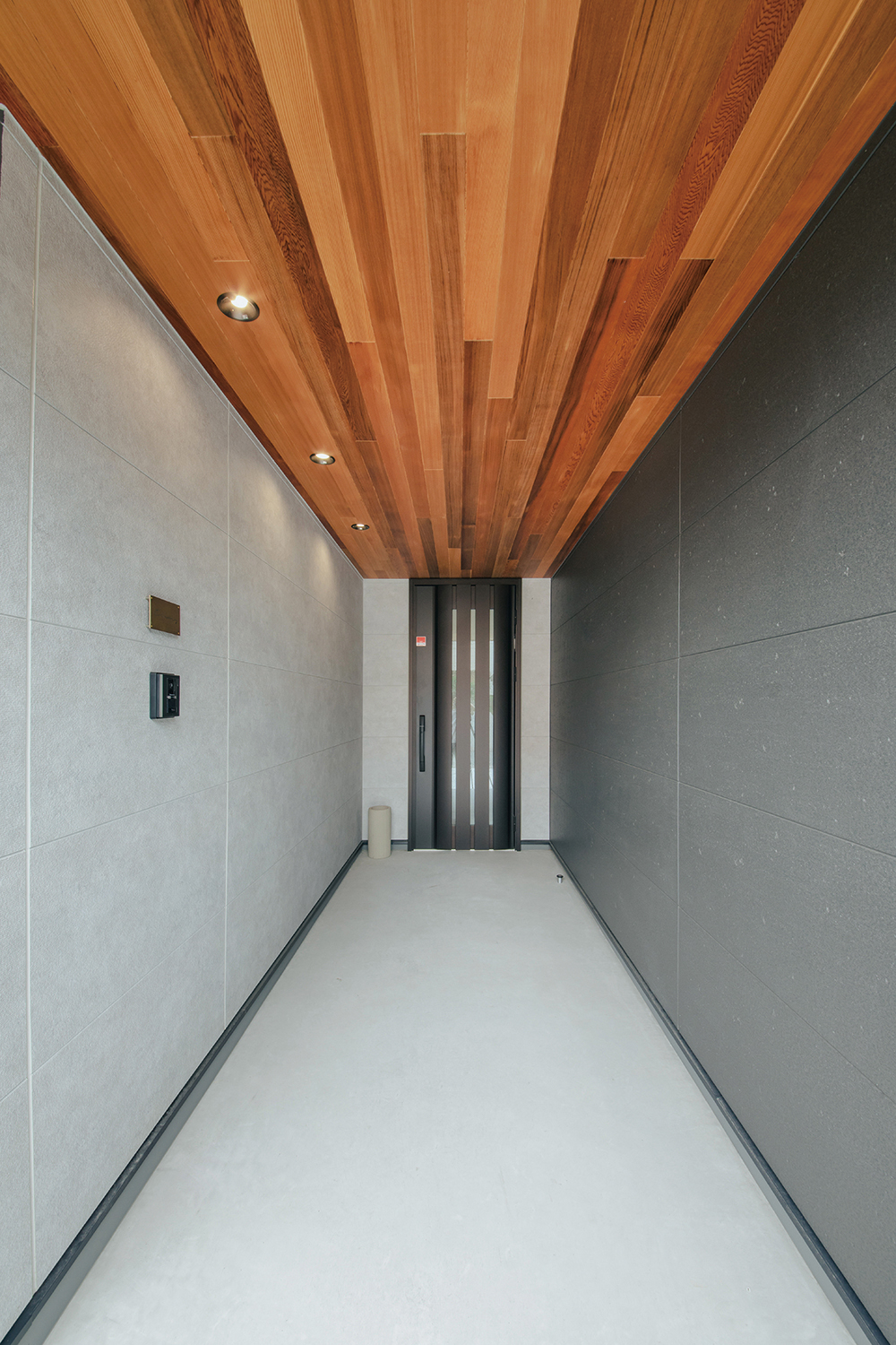 will建築工房【デザイン住宅、間取り、インテリア】グレーの濃淡でまとめた外壁に、レッドシダー張りの天井を組み合わせて、アクセントを付けた玄関。内と外の統一感を意識して、リビングの天井やバルコニーの軒天井にもレッドシダーを用いている