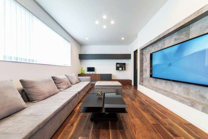 4人一緒に並んでもゆったりのソファ。大画面テレビの配線も見えない収納デザイン。子どもが走り回っても余裕のリビング