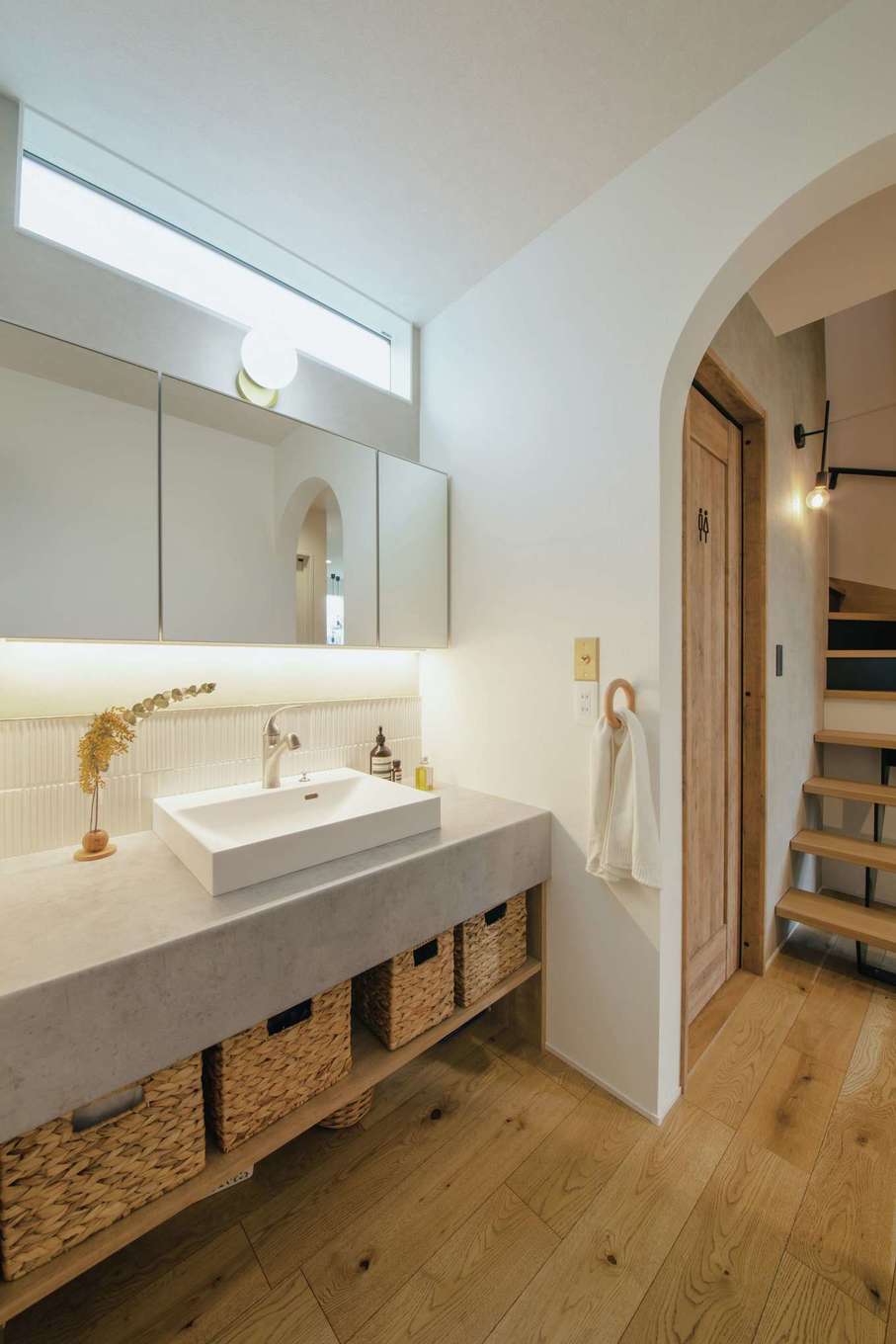 will建築工房【デザイン住宅、間取り、インテリア】ヘアメイクスタジオに隣接して設けた、造作の洗面スペース。鏡の裏面には収納、下部には間接照明を仕込み、カウンターや洗面ボウルを照らす。ハイサイドライトも設け、明るさも確保した