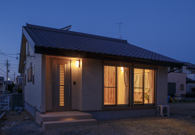 シニア世代の夫婦が2人で暮らすにはちょうどいいサイズの平屋建て。ポーチの階段下に足元灯を設置したことで、シンプルな外観にニュアンスがプラスされた