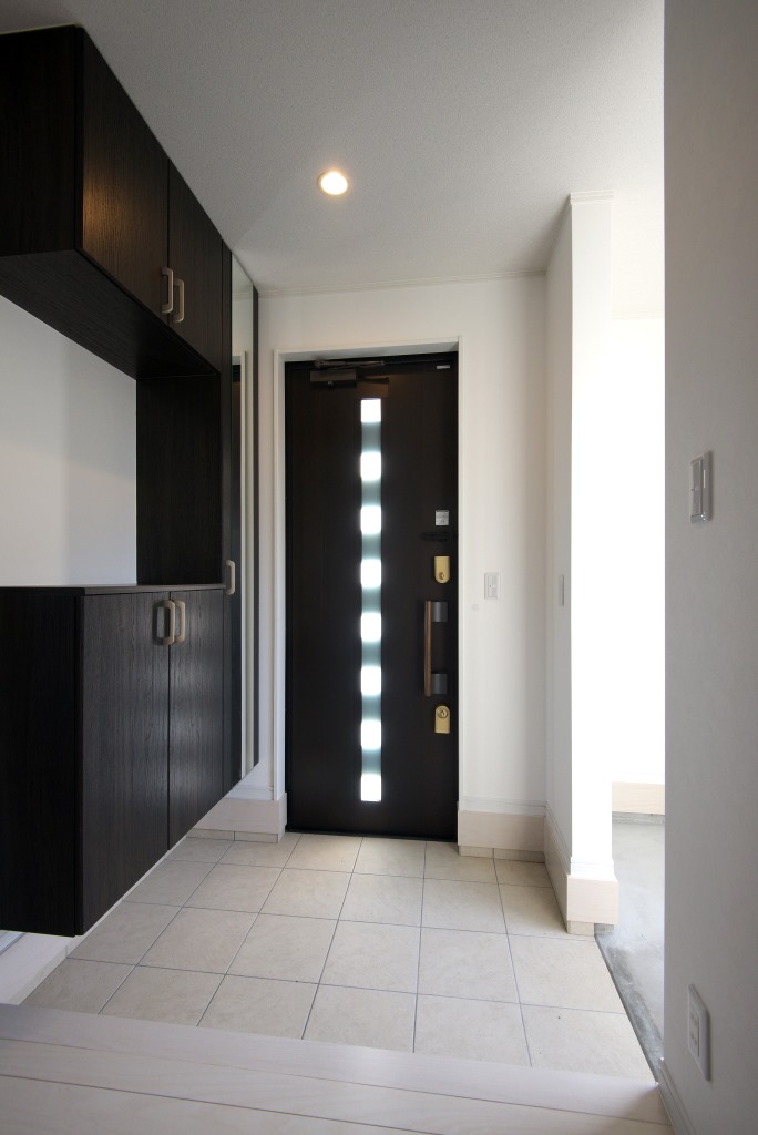 メテックス建築事務所【1000万円台、子育て、省エネ】ドアのガラス部分からは光が差し込み明るい玄関。その横には土間の収納も備えられている