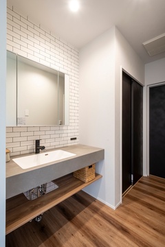 シンプルで機能的な洗面スペース。壁には白いタイルが貼られ、デザイン性と実用性を兼ね備えた空間。