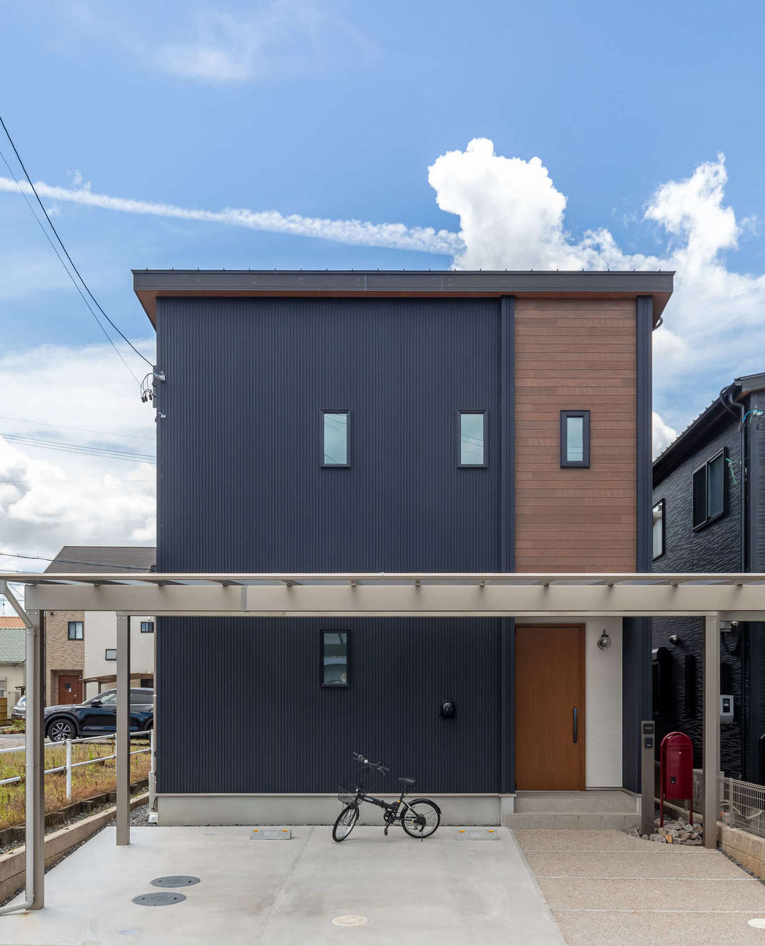ユートピア建設【収納力、省エネ、インテリア】ダークグレーのガルバリウムと木目のサイディングが絶妙に融合した外観デザイン。片流れの屋根に8kWのソーラーパネルを搭載。許容応力度計算による耐震等級3の安心構造で長く安心して暮らせる
