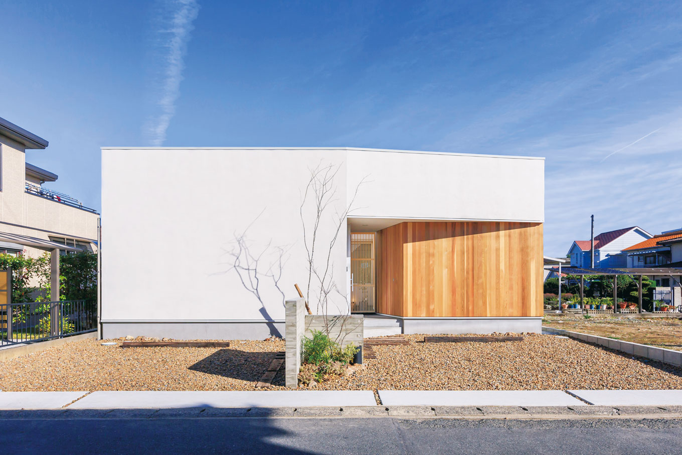 ARRCH アーチ【狭小住宅、建築家、平屋】55坪の敷地に4台分の駐車スペースを確保し、延床26坪の平屋を実現。外観デザインはシンプルな白い箱型で、板張りの壁が美しく映える。プライバシーに配慮し、道路側には窓を設けていない