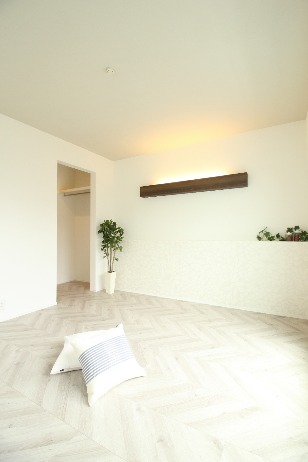 小野田産業～designers house project～｜明るい自然光が差し込む居室。壁の間接照明と白を基調としたインテリアが、空間を穏やかで落ち着いた雰囲気に演出している。