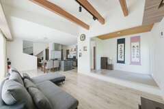 リビングの天井は勾配天井にして梁を見せるデザインに。ひと続きの空間も、天井高を変えることでゆるやかにゾーニング。奥行きやデザイン性も演出できる