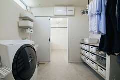 洗面スペースに隣接したランドリー兼脱衣スペース。子どもの靴などを洗えるようにスロップシンクも設置。下着やタオル類をしまう収納や、室内干しのハンガーも確保し、洗濯の家事が1か所で完結する