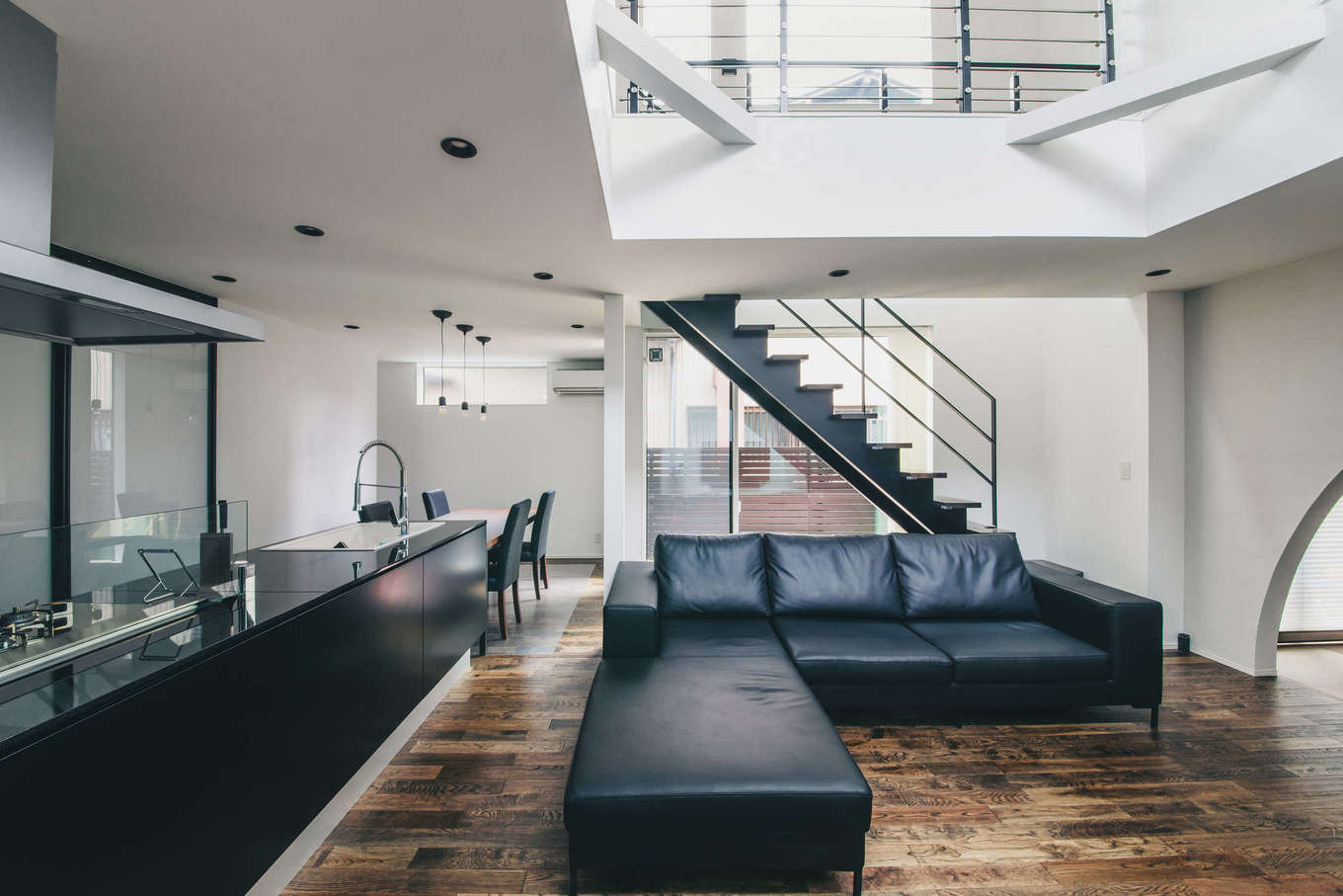 nattoku住宅【デザイン住宅、収納力、間取り】白・黒・木目を基本にコーディネートしたモダンなLDK。L字型の本革のソファ、オブジェのように美しいアイアンのスケルトン階段、宙に浮かんでいるようなおしゃれなキッチンと、どれも『nattoku住宅』オリジナルによる標準仕様だ