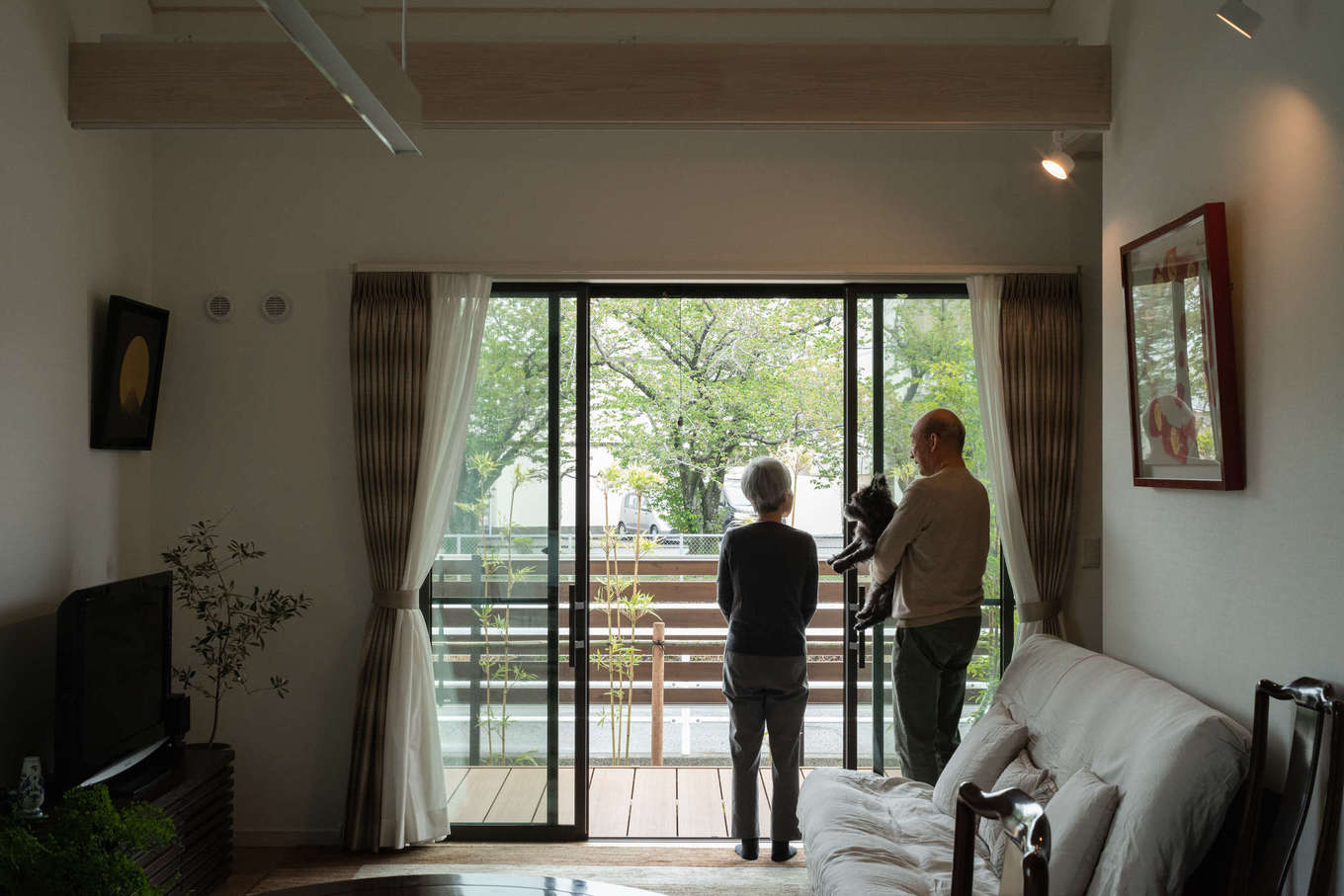 石上建設【省エネ、夫婦で暮らす、平屋】目の前には小川が流れ、その向こうには桜並木。窓の外に続くウッドデッキがリビングの広がりを演出しつつ、多様なくつろぎを生んでいる