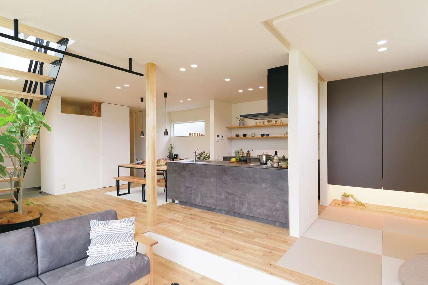 住家 JYUKA【デザイン住宅、間取り、建築家】明るいオーク材に合わせて白とグレーを基調にしたLDK。天井にはアイアンバーも取り付け、子どものブランコを吊る楽しい未来の予定も。奥さまお気に入りの造作オリジナルキッチンは、OB宅を見学し実際の使い心地や便利なオプション情報も聞き、細部にまでこだわりを盛り込んだ。畳コーナーにはロールスクリーンを取り付け、空間を仕切ることも可能