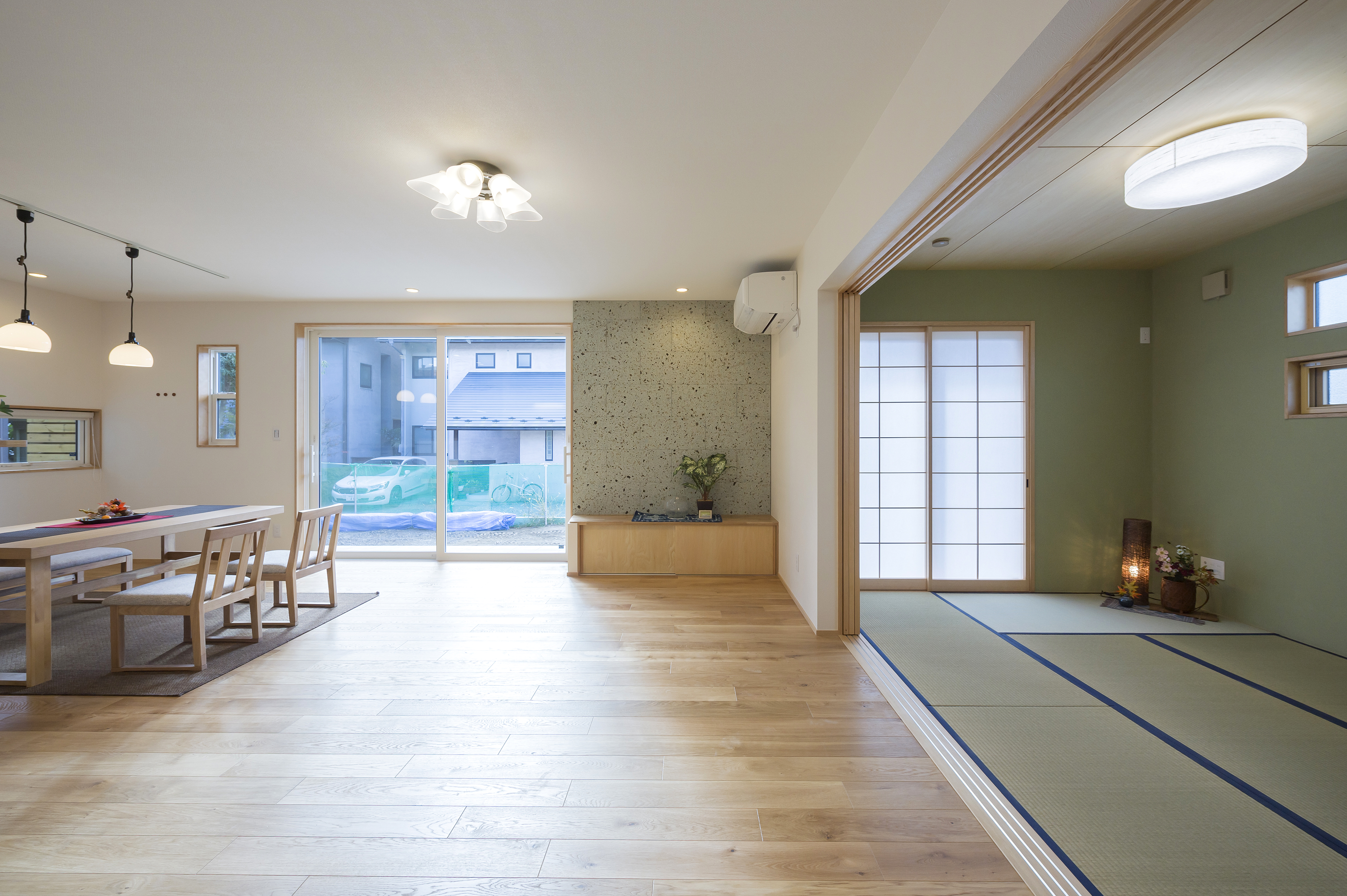 しあわせの住まい一級建築士事務所｜広々としたLDKと和室が一体となった空間。大きな窓から光が差し込み、開放感がある。和モダンな雰囲気が融合した設計で、家族団らんに最適である。