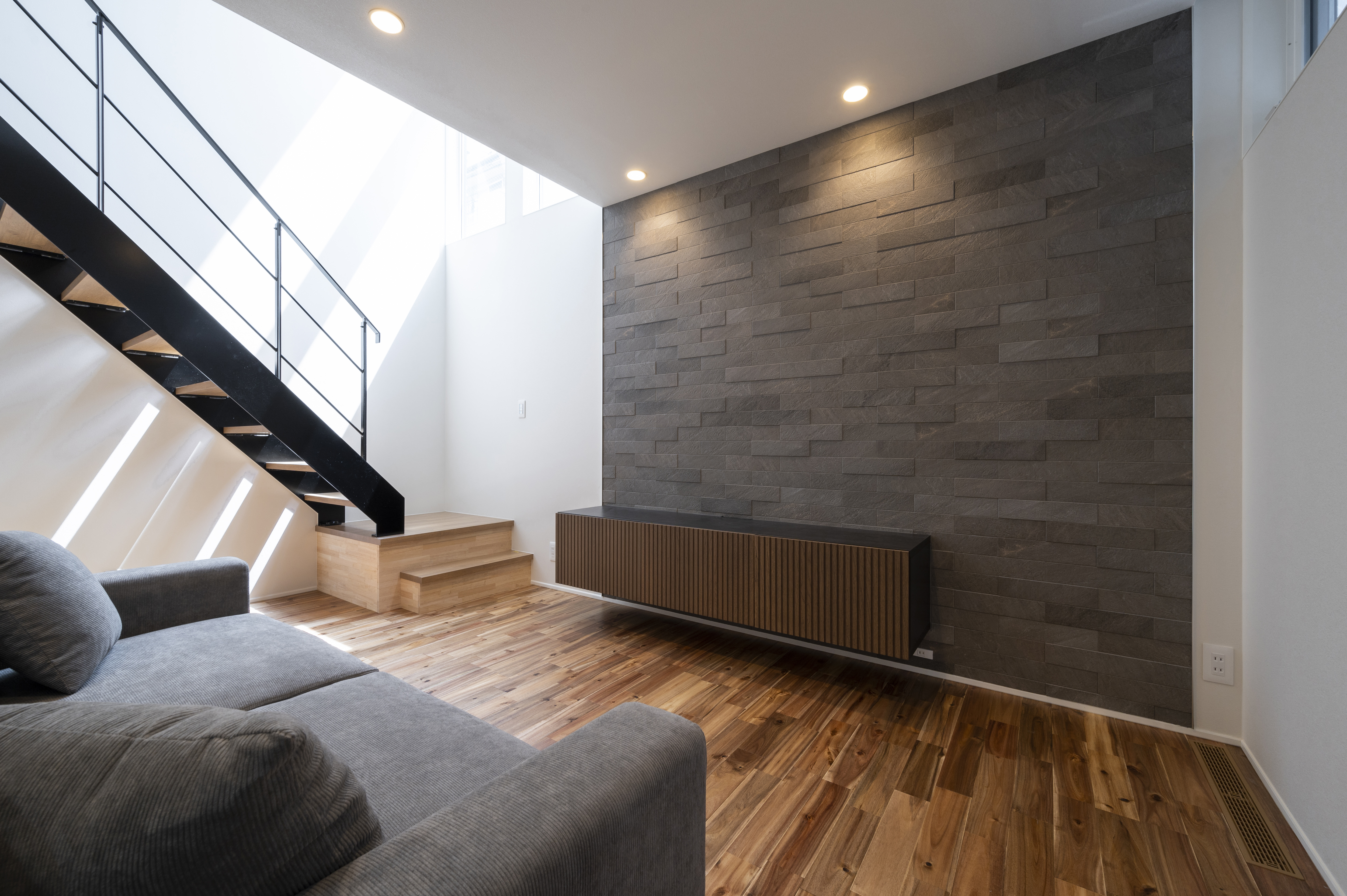 オネストアーク｜モダンなインテリアが魅力のLDK。シンプルなデザインの中に、スタイリッシュな照明と落ち着いた色調の壁が調和している。階段のデザインも印象的で、空間にアクセントを加えている。