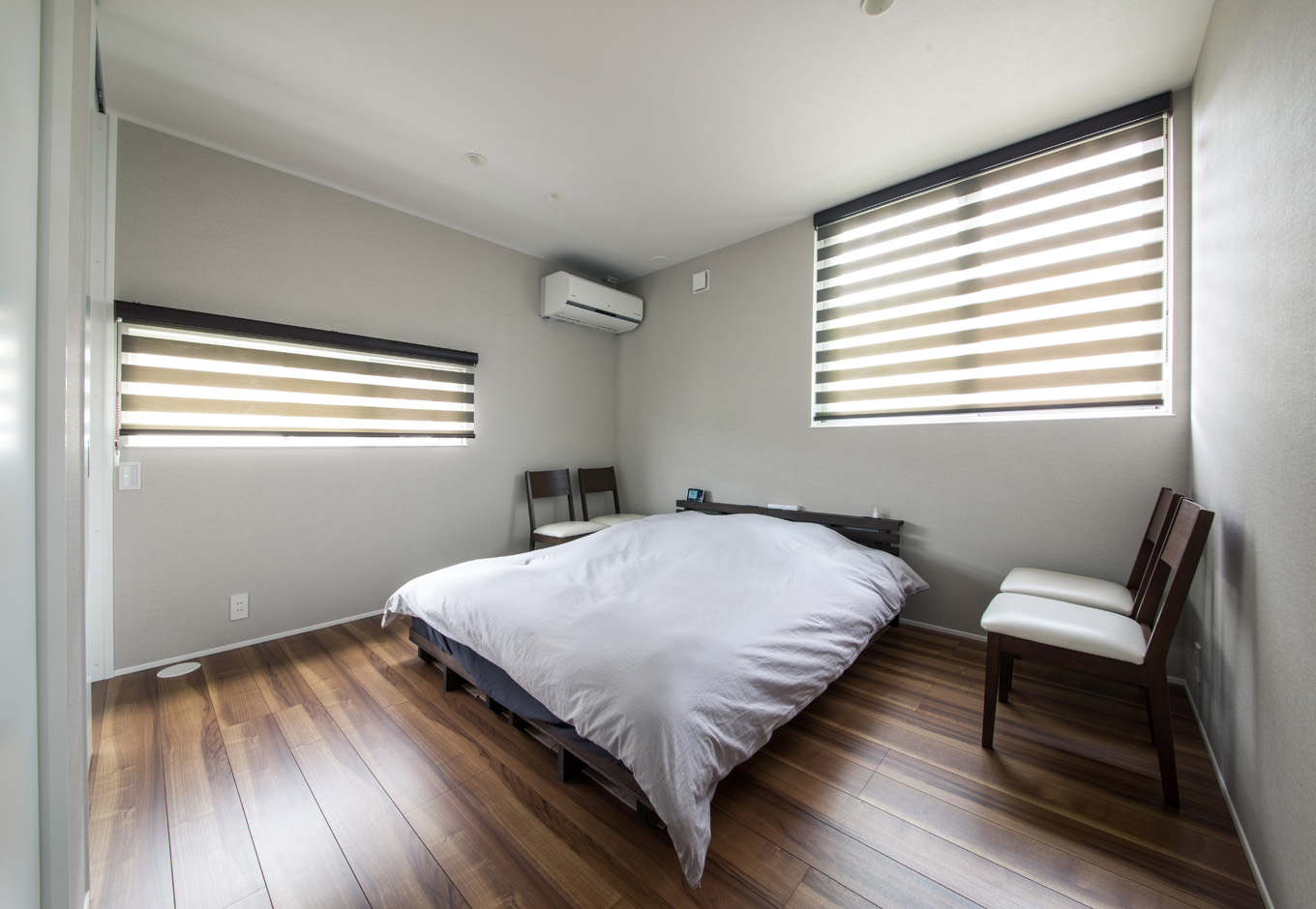 SEIEN ARCHITECT【デザイン住宅、建築家、インテリア】2階の寝室はシンプルで無駄のない空間。２方向に窓を設け、明るさと風通しに配慮した。道路に面した壁側は、周囲の視線に配慮して横長の窓を設置