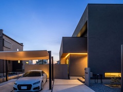 シンプルで直線的なフォルムのカッコいい外観。
外壁は濃いグレーをベースに、軒天に木目調を取り入れ、スタイリッシュな中にも温かみを感じられるデザインになっています。
さらに、掃き出し窓から玄関アプローチにかけて、間接照明を取り入れたため、夜には穏やかな光が照らし出し、ラグジュアリーな雰囲気になっています。