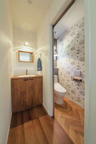 家族が使用する2階トイレは奥さまの好きなアメリカ映画のクロスを採用し、遊び心をプラス。隣の洗面台も雰囲気にフィットする