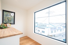 大きな窓から自然光が差し込むフリースペース。木製カウンターが温かさを添え、多目的に使える空間が広がる。