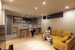 LDKでくつろぐ夫妻。おしゃべりをしながら、ゆったりと過ごす時間がお気に入り。ショップで一目惚れした山吹色のソファがライトグレーのクロスにマッチ