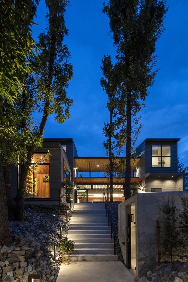 豊かな自然に囲まれたモダンな住宅の外観。夜間の照明が建物をさらに引き立て、洗練された雰囲気を演出している。