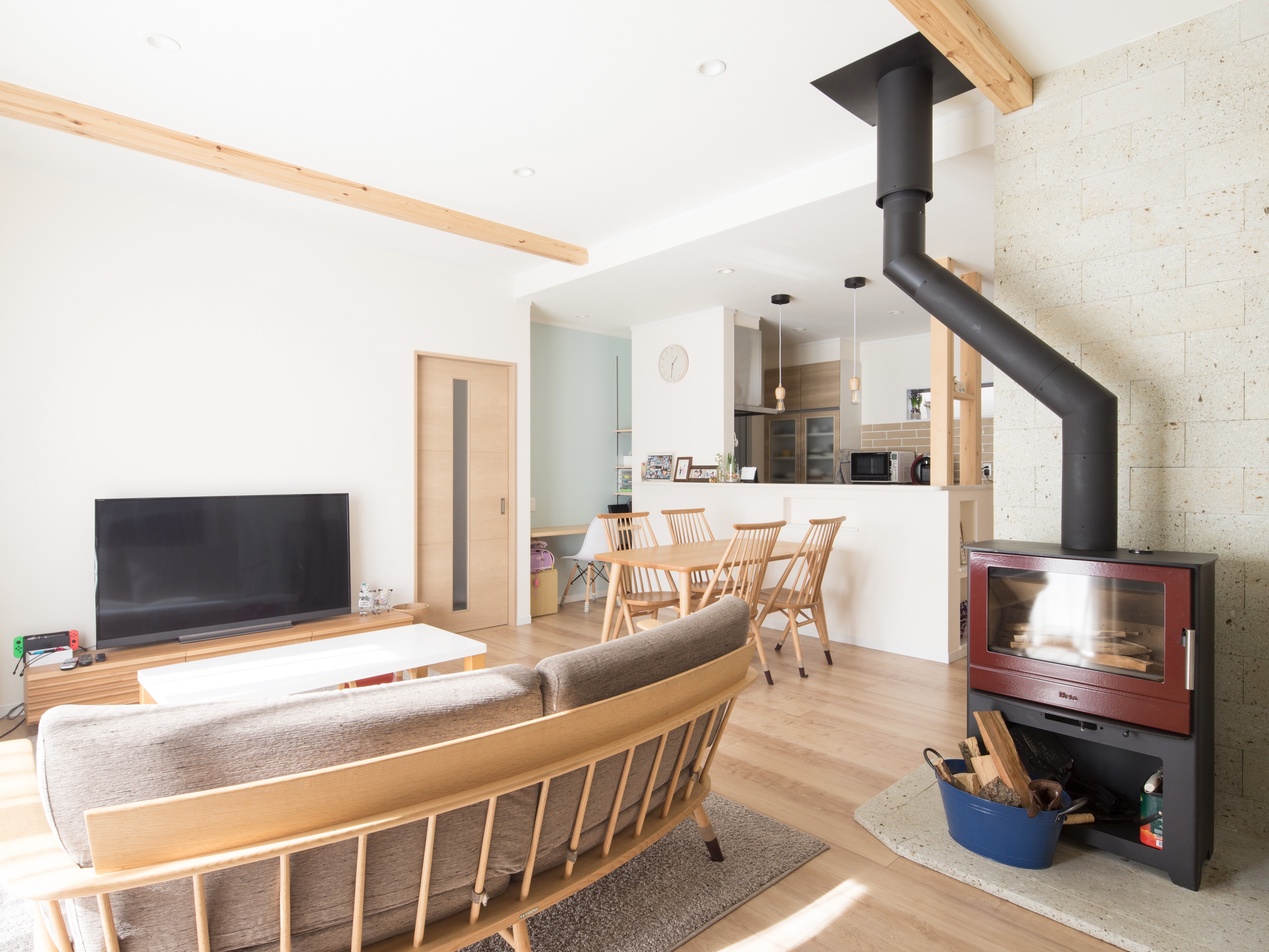 エスホーム｜モダンな薪ストーブのあるLDK。広々とした空間に木製家具が温かみを添え、ナチュラルで落ち着いた雰囲気を演出している。