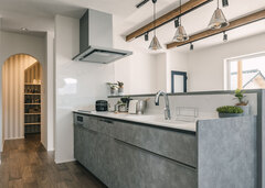 モルタルで仕上げたキッチン。パントリーの間に通路を挟むことでぐるっと回遊できる家事動線に