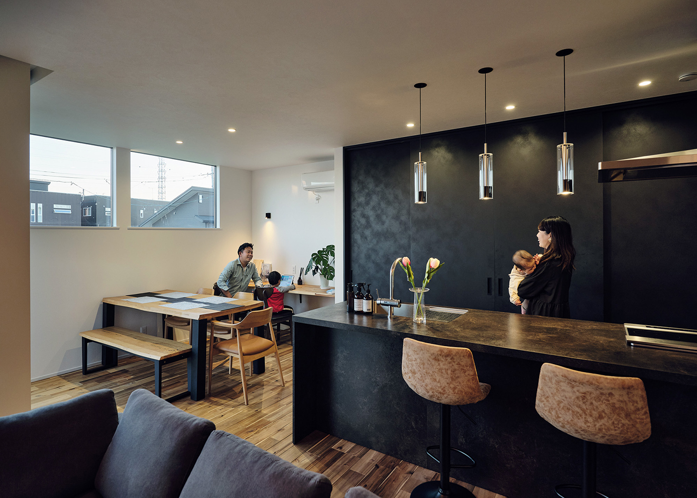 平屋建築ブルーハウス【デザイン住宅、間取り、平屋】キッチン背面には黒いハイドアの「隠す収納」を採用し、生活感を排除。シックなカフェのようにスタイリッシュなダイニングキッチンが実現した。バックヤードにはファミリークローゼットと水回りが並び、計算された家事動線が日常生活の時短も叶えている