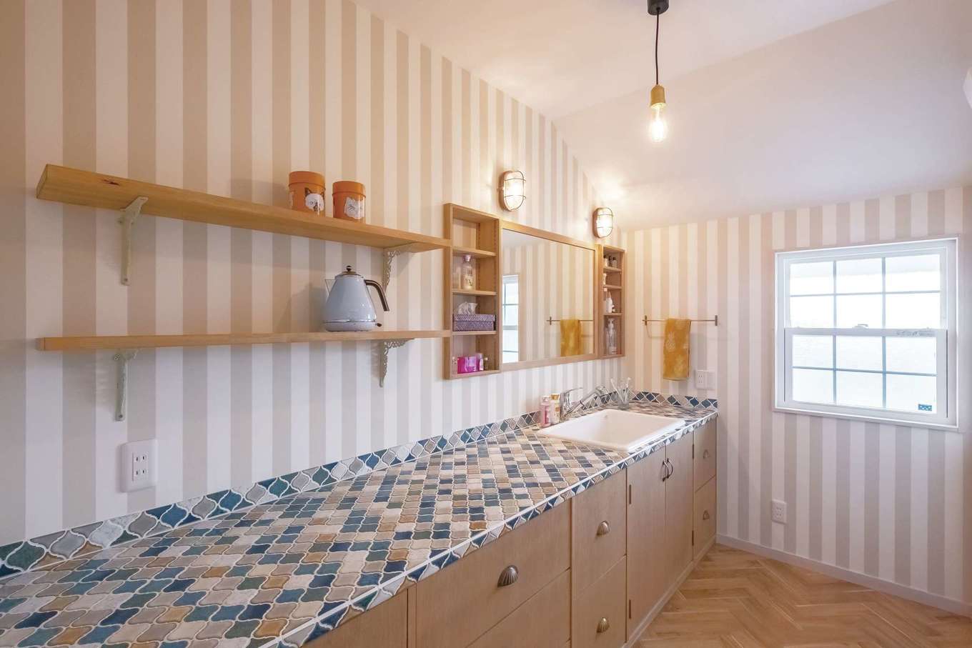 富士ホームズデザイン【デザイン住宅、子育て、インテリア】Iさん夫妻用の洗面脱衣室は、やさしい色合いのクロスやタイルでナチュラルな雰囲気。洗面化粧台、棚、鏡なども希望にあわせて造作してもらった