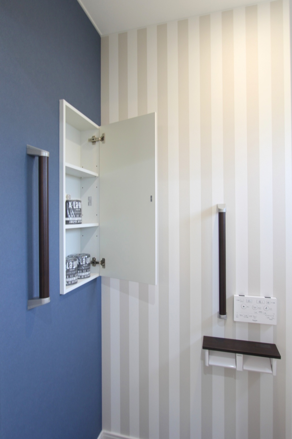 ナイスホーム｜トイレの壁面には扉付きの埋込収納棚を設置。ストライプのクロスにブルーがアクセントとなり、空間に深みを与えている