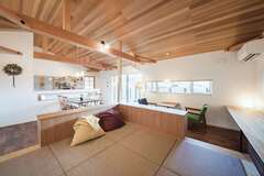 22畳のLDKにL字型の造作収納を設けて、緩やかに仕切ったことが使いやすさの秘密。畳の代わりにクッションを選んだ小上がりスペースは、寝転びながら子どもと遊んだり、天井を見上げたりと快適に過ごせる