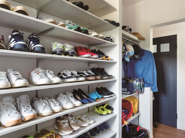 ご主人のスニーカーコレクションが整然と並ぶ玄関クローゼット。上着やリュック、傘など、さまざまなものを収納できるようにポールと可動段どちらも取り入れています。
