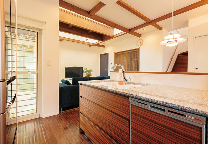 エボニーの木目パネルが料理タイムを楽しく演出する『納得』オリジナルキッチンREGALOⅢ。広めのワークトップは御影石。ダイニングの美しいペンダントライトはルイス・ポールセン。ドアを開けると、リゾート感ただようテラスへと続く