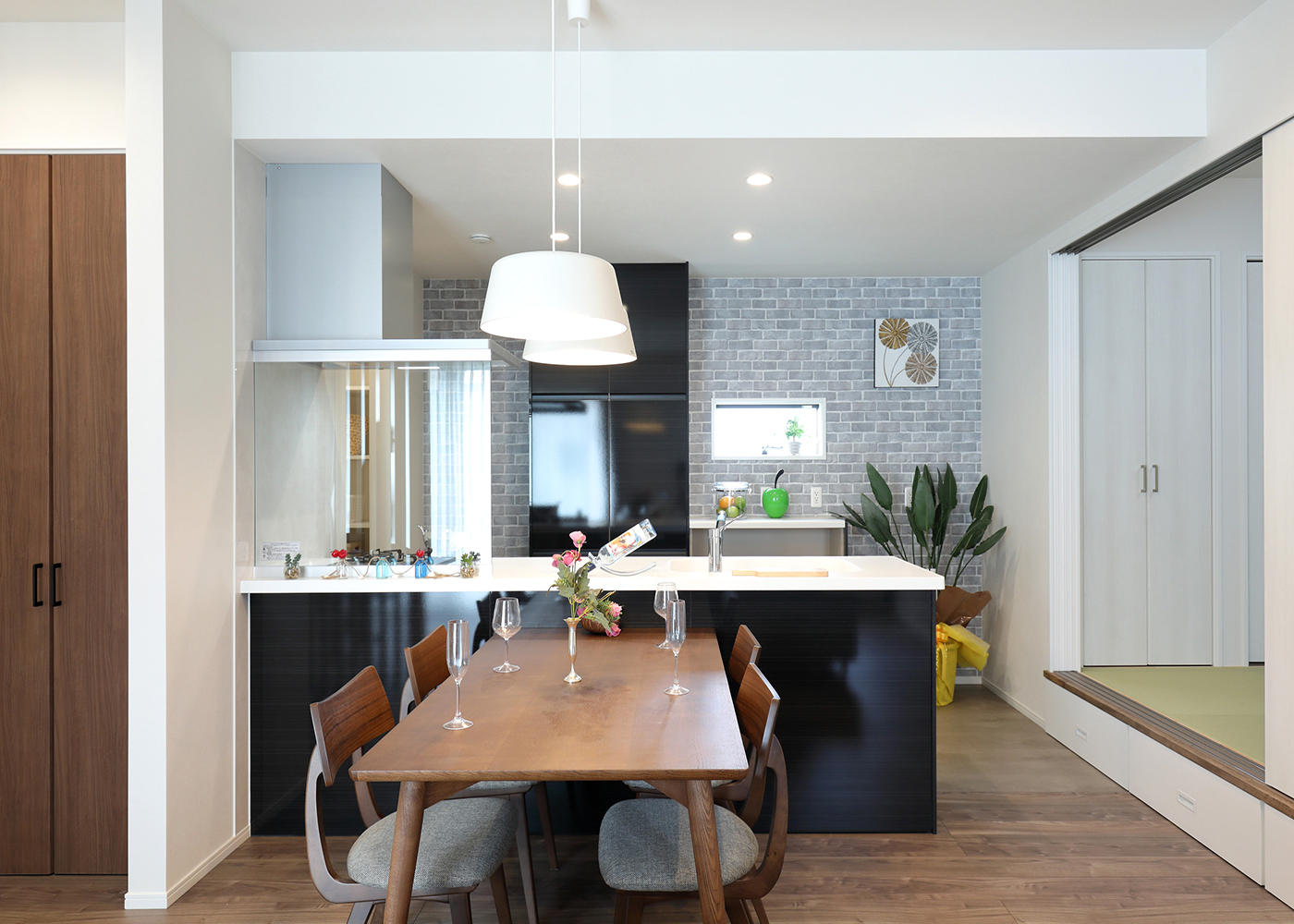 丸昇彦坂建設【デザイン住宅、和風、間取り】ダイニングキッチンは下がり天井にして、落ち着きのある雰囲気に。ペンダント照明やアクセントクロスを用い、ご家族の個性を演出した