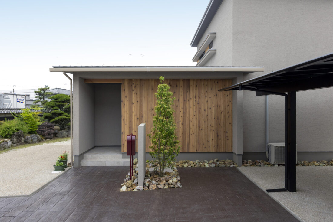 チェックハウス｜モダンなデザインの玄関。木材が使われた外壁が自然と調和し、訪れる人を迎える洗練されたエントランススペース。