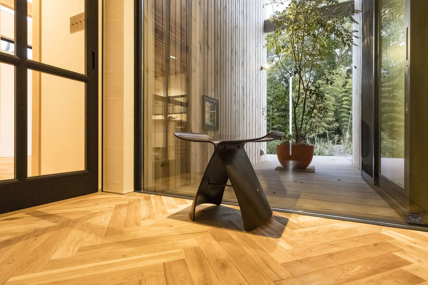 Hands Works（アオイ建築）【デザイン住宅、収納力、自然素材】高級感を醸し出すヘリンボーン張りの床にバタフライスツールが映える。大きなFIX窓の向こうには竹林が広がる