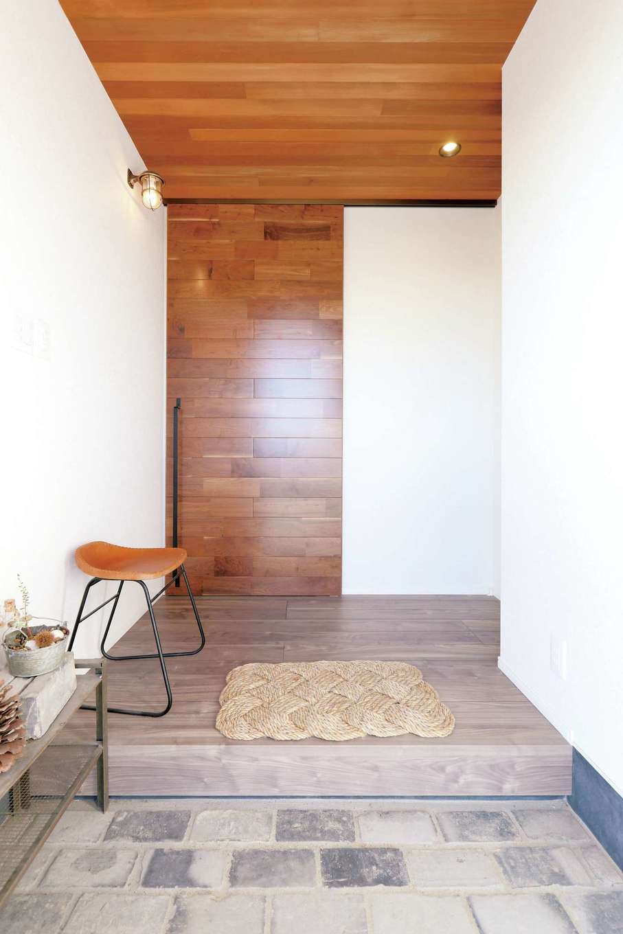 丸昇彦坂建設【デザイン住宅、趣味、インテリア】玄関、リビングドアの天壁に異なる種類の部材を採用しながらも一体感を出した。三和土はアンティークレンガ。マリンランプも映える独創的な空間