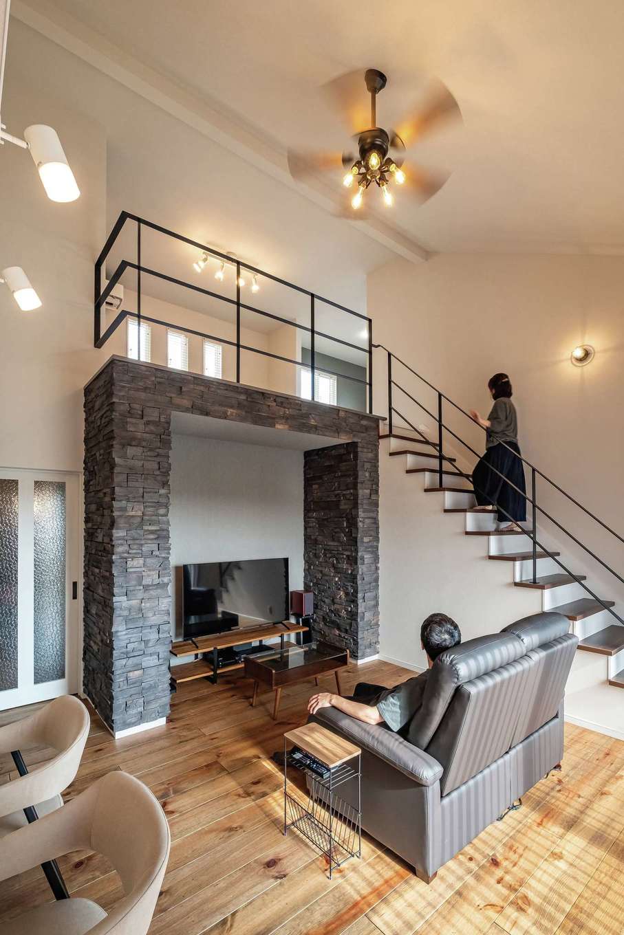 アフターホーム【デザイン住宅、趣味、間取り】広々と開放的な吹抜けのリビング。テレビステーションを天然石で囲んだことで、高級感が生まれた。シャビーシックな無垢の床と繊細なアイアンの手すりがベストマッチ。これだけの大空間でも、同社ならではの高い断熱・気密性能で上下階の温度差が少なく、冬も夏も快適に過ごせる