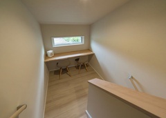 スキップフロアを活かして設けた家族共有のワークスペース。スリット窓からのどかな景色が見える。階段を上がると小屋裏へ