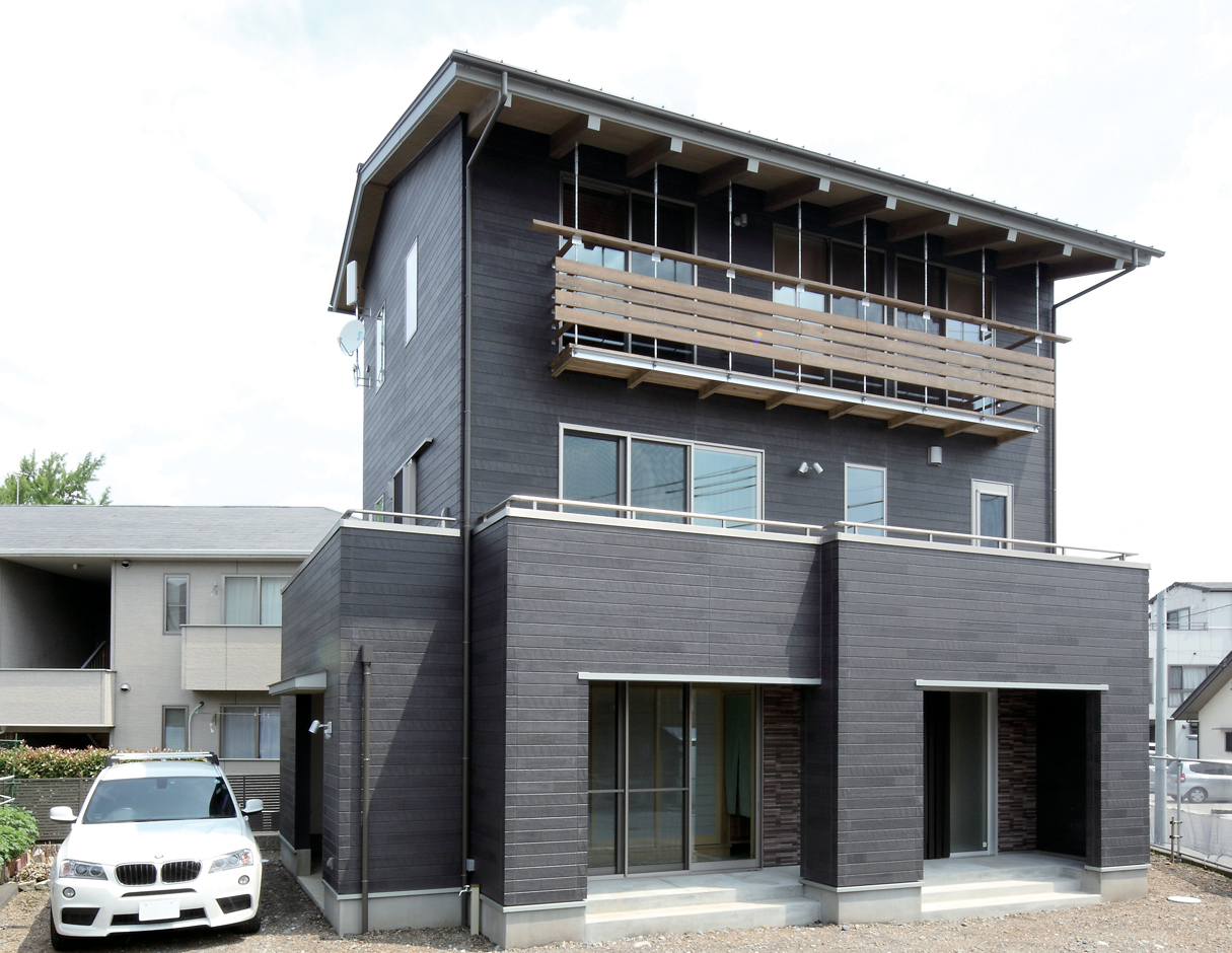 アクトホーム【自然素材、省エネ、間取り】外壁は雨垂れなどの汚れが目立たない黒を選択。建物周辺に5つのバルコニーを設け、外からの視線を遮り、窓を開けて風や光を通す。また物干し、ゴミのストック、ミニ家庭菜園としても大活躍だ