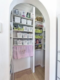 小型スペースを有効活用したパントリー。さまざまな収納ボックスが整然と並んでおり、日用品や食品をスッキリと整理できる設計。カーテンで仕分けが可能で利便性も高い。