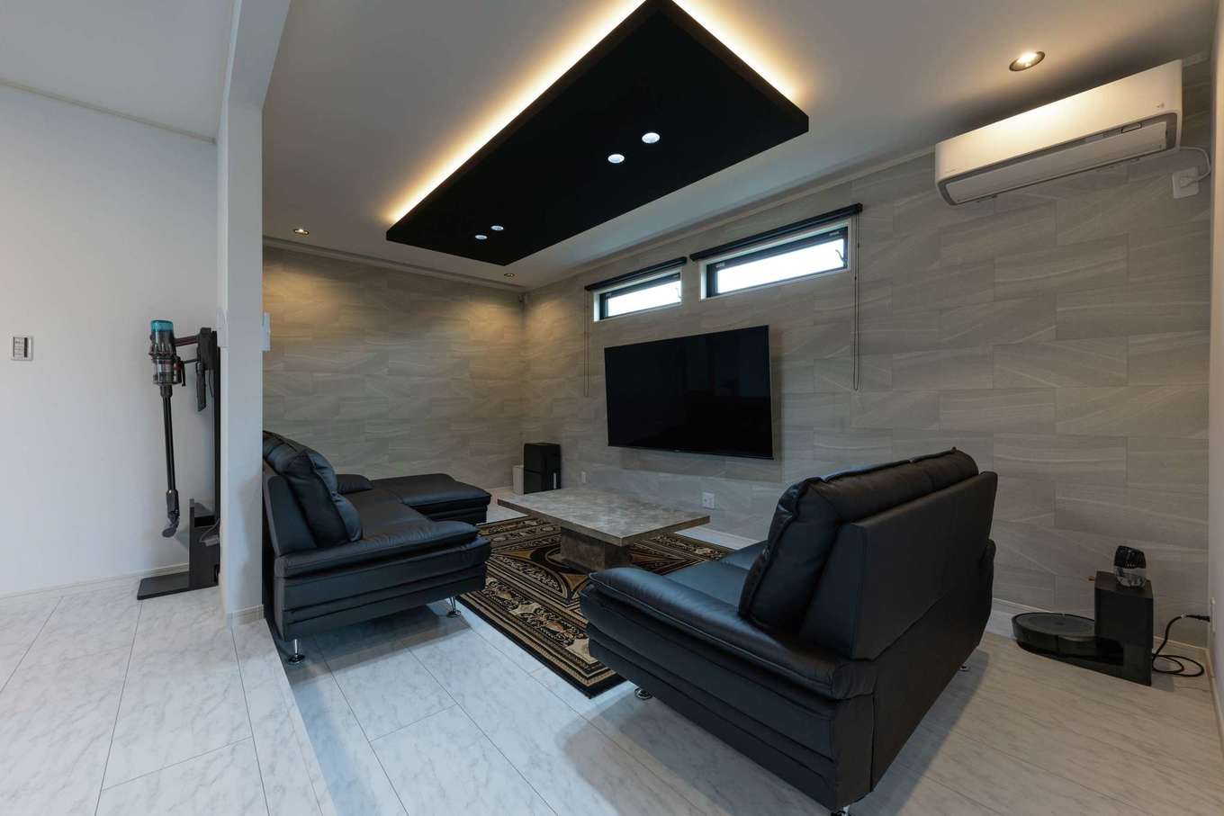 サンワ開発【デザイン住宅、収納力、ガレージ】リビングは一段下げてダウンフロアとし、間接照明を施した折り下げ天井を採用した。奥の壁際の天井にはプロジェクターの電動スクリーンが設置されている