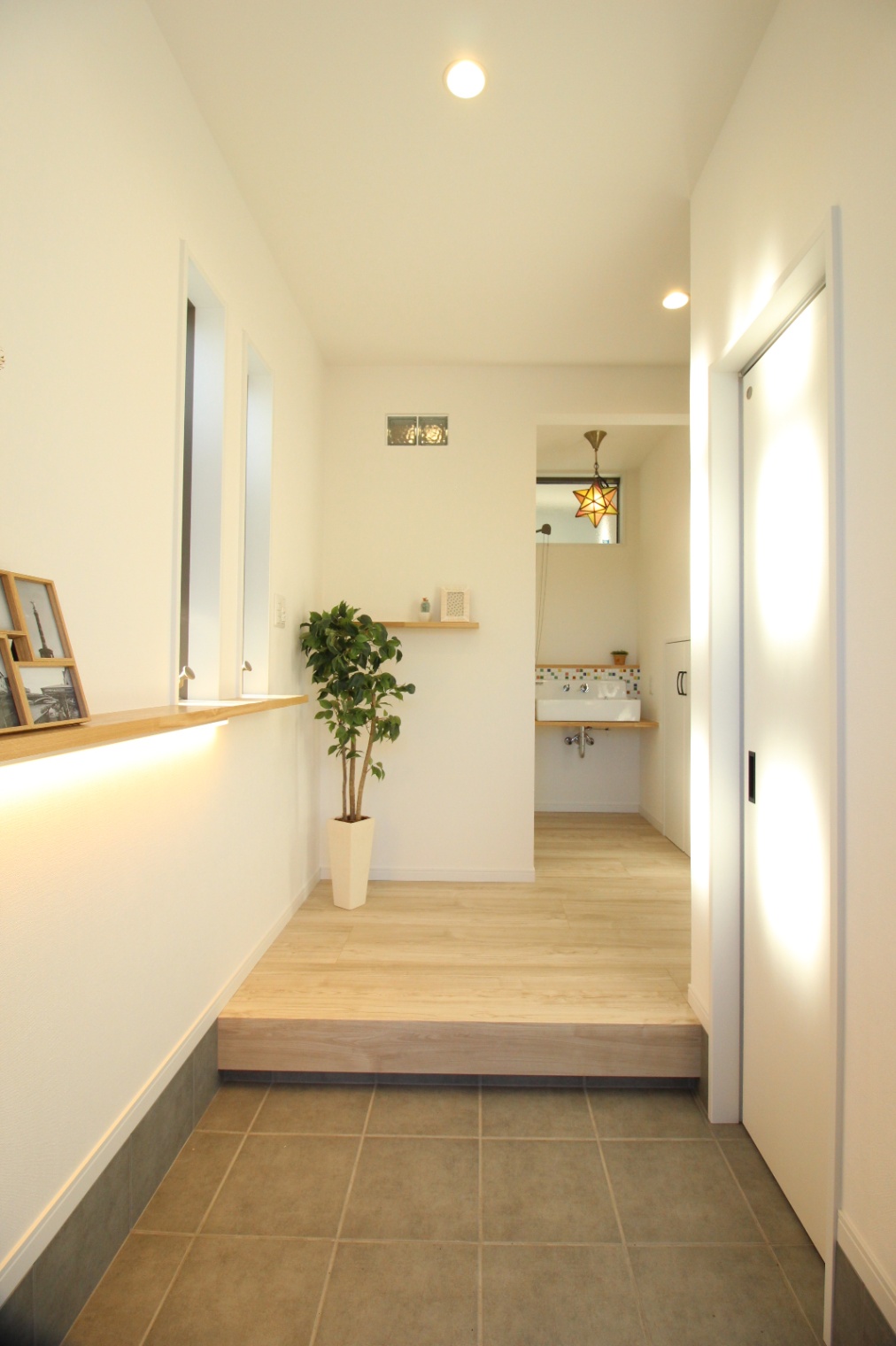 小野田産業～designers house project～｜明るい照明により開放感を感じさせる玄関ホール。洗練されたデザインの中に観葉植物がアクセントを添えている。