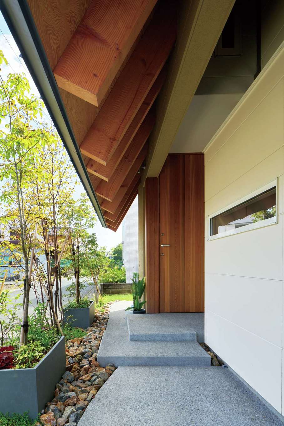 MABUCHI【デザイン住宅、間取り、建築家】深い軒に守られたアプローチ。スリット窓はご主人の書斎で、外から覗かれることもなく、庭の景色を楽しむことができる