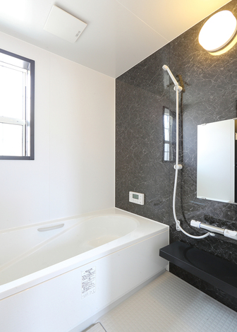 ユニットバスの正面に黒のストーン調のアクセントパネルが重厚感を放つ。サッシと合わせることにより全体の印象に統一感を与える