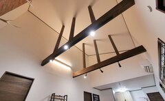 リビングルームの印象的な高天井と露出梁が強調されたデザイン。自然光が差し込み、開放感を楽しめる空間