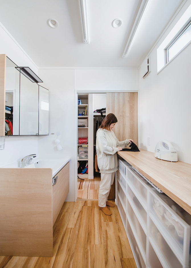 玄関からもリビングからもアクセスしやすい、ゆったり広々としたランドリー。ハイサイドライトからの光で明るさもしっかり確保。家族それぞれの衣類をしまう収納BOXが入る長いカウンターを造作したほか、ガス衣類乾燥機「乾太くん」も備えたことで、「洗う・乾かす・アイロンがけ・たたむ・しまう」を一か所で完結できる。共働きで子育て夫婦の家事時間を大幅に短縮でき、家族団らんの楽しい時間が増えたと喜んでいる