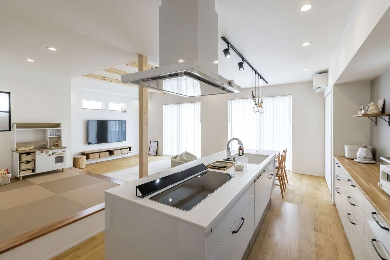 SEVEN HOUSE/セブンハウス【子育て、収納力、間取り】奥さまお気に入りのアイランドキッチンを中心に、ぐるぐると回遊できる動線が便利。キッチン、カップボード、調理家電をすべて白でコーディネートし、ナチュラルな空間に統一感が生まれた。大きな開口部から入る光と風も心地いい