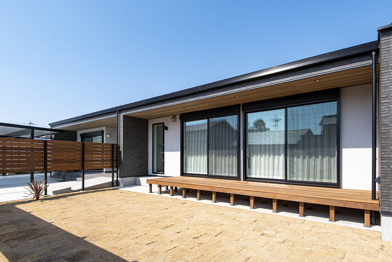 トキワハウス デザイン アンド ビルド（常盤工業）｜白い壁と大きな窓が特徴のモダンな住宅の縁側。広々としたデッキスペースがあり、リラックスできる開放的な空間を提供している。