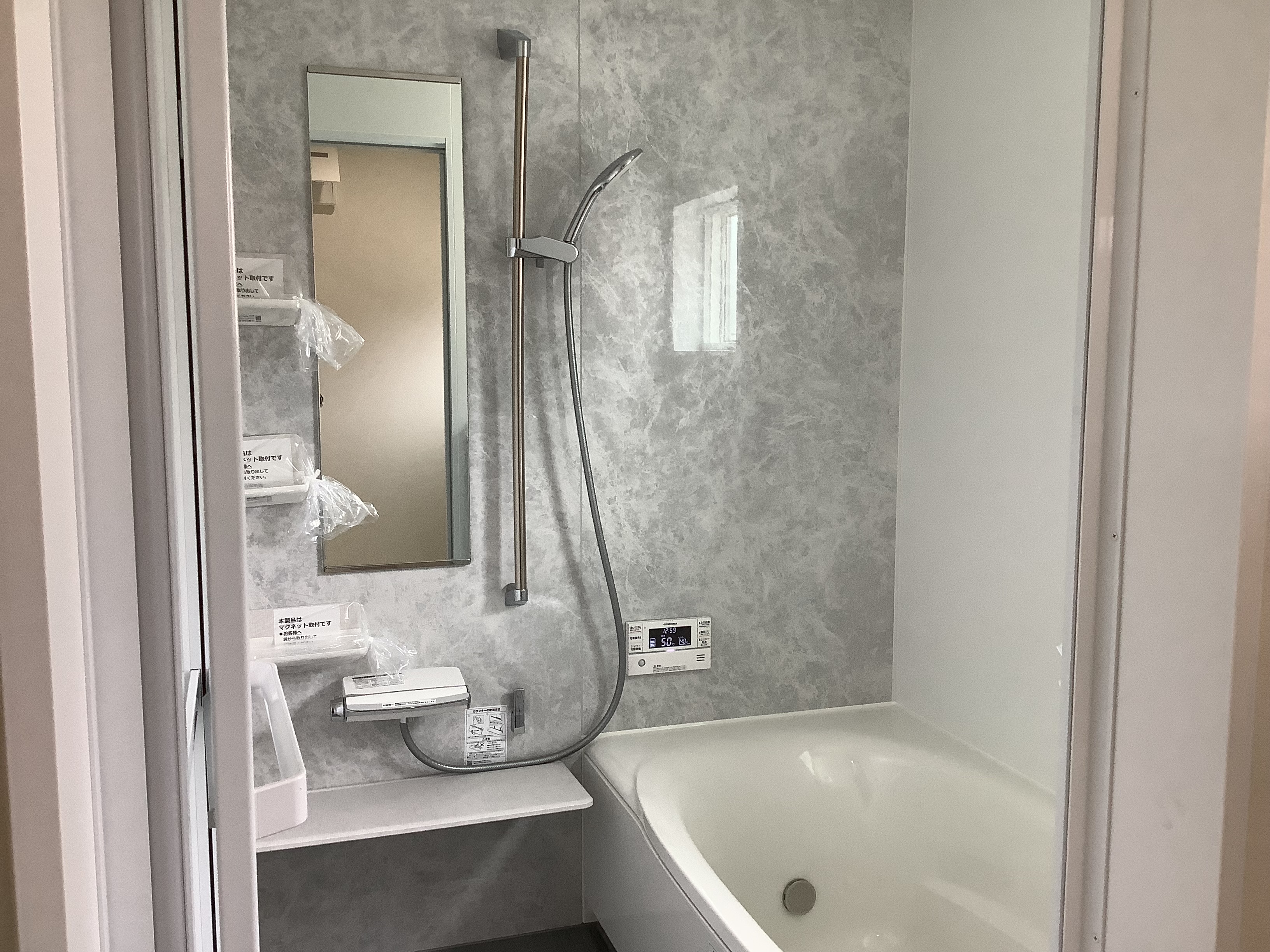 フロート・ハウス｜シンプルで機能的なバスルーム。壁面のグレーの模様が落ち着いた雰囲気を醸し出し、洗練されたデザインが魅力的である。