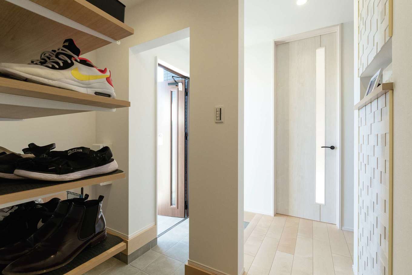 HAPPY HOUSE（山田工務店）【デザイン住宅、子育て、間取り】広くて使い勝手のいいシューズクロークを備えた玄関。右側の壁はエコカラットを採用