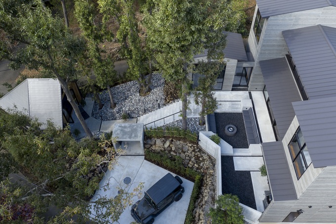 自然豊かな環境に囲まれたモダンな建物の外観。特徴的な屋根と庭園が調和し、洗練されたデザインを際立たせている。