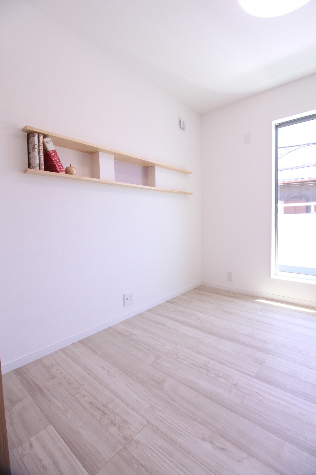 小野田産業～designers house project～｜シンプルで洗練されたデザインの居室。明るい日差しが差し込む窓とナチュラルな木製の棚が、部屋全体に温かみを与える。